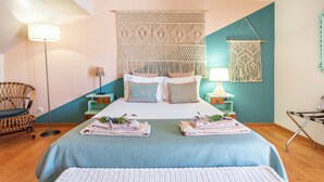A bedroom with a bed, two nightstands, a floor lamp, a macrame wall hanging, and a chair. - Downtown Alegria B&B (Tavira)