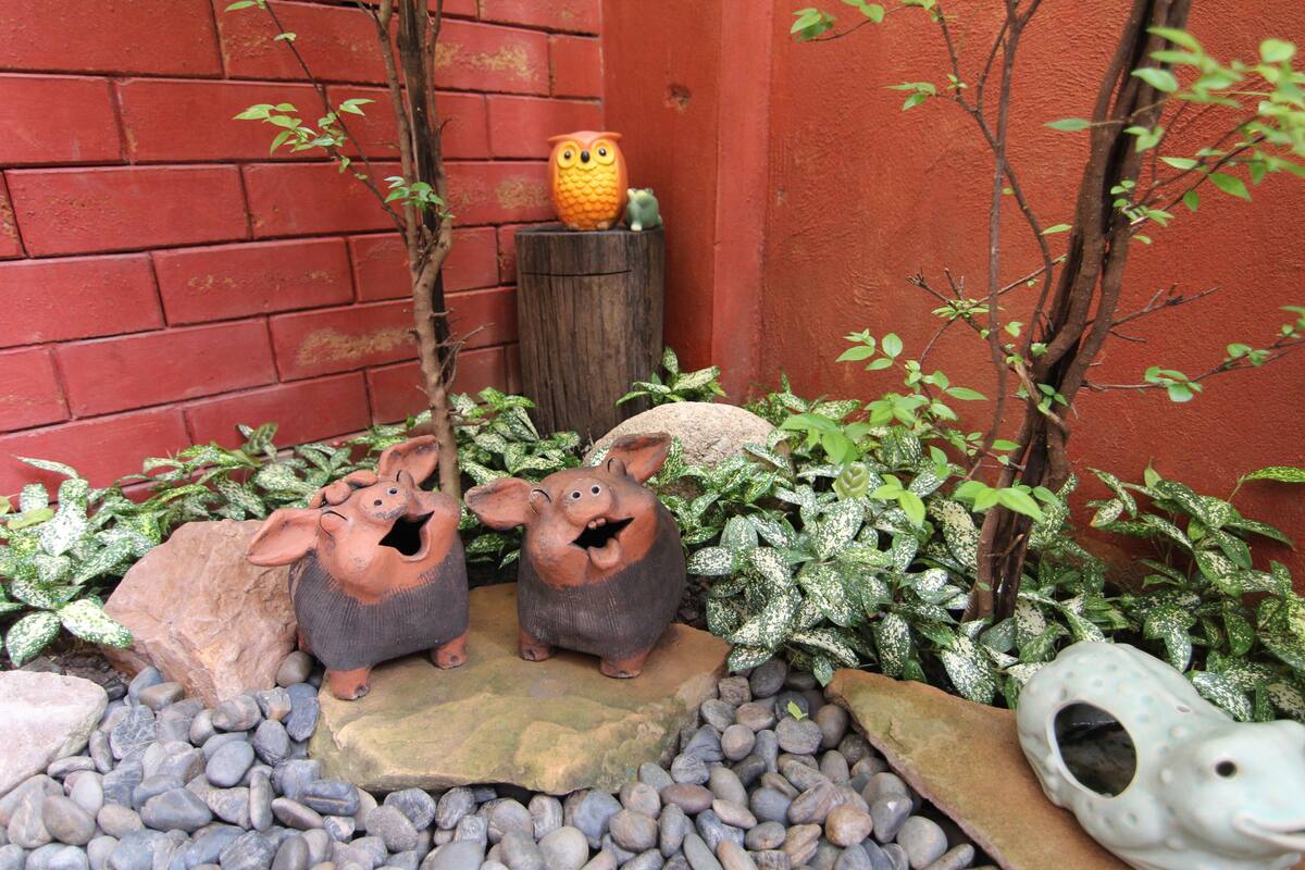 Een tuin met decoratieve beeldjes van dieren, een houten paal en een klein uilbeeld.