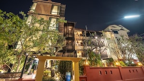 Een modern hotel met meerdere verdiepingen, buitenverlichting en een goed onderhouden tuin.