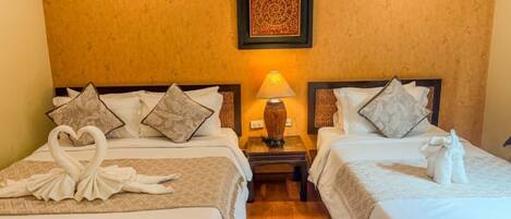A hotel room with two beds, a nightstand with a lamp, and a framed artwork on the wall.