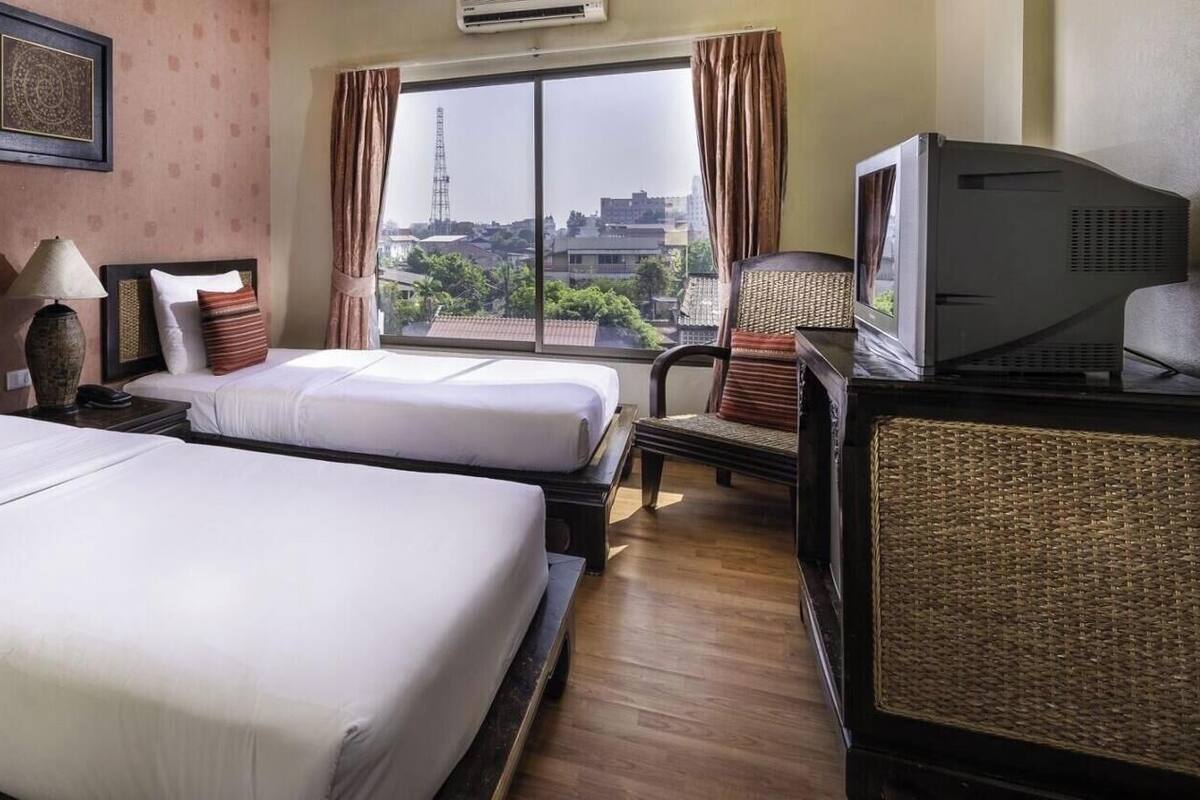Een hotelkamer met twee bedden, een televisie en een raam met uitzicht op de stad.