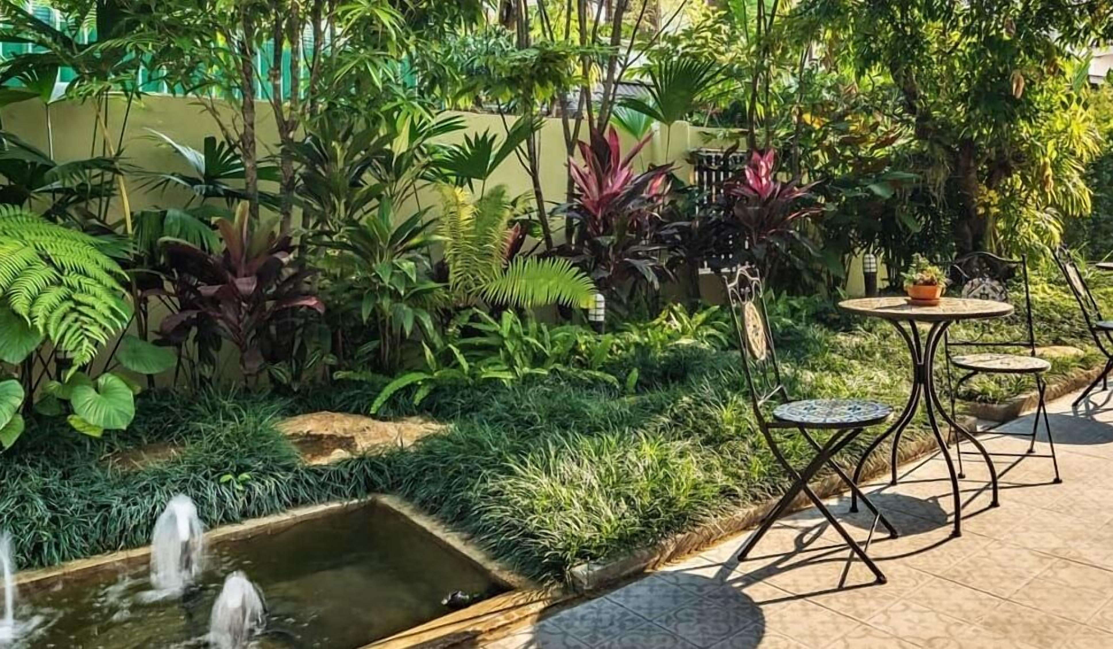 A garden with a water feature, lush greenery, and outdoor seating.