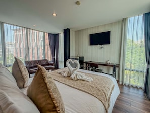Une chambre d’hôtel avec un grand lit, un bureau, une télévision et une vue sur l’extérieur.