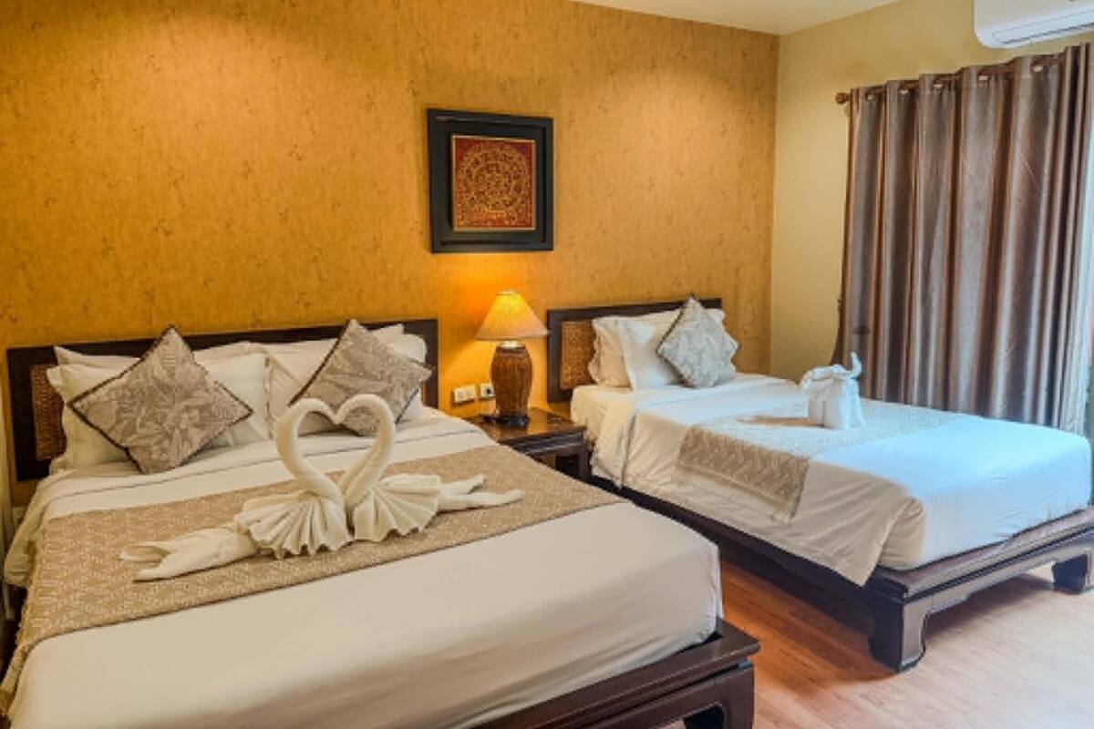 Hotelkamer met twee bedden, een nachtkastje met lamp, een lijst op de muur en een raam met gordijnen.