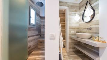 Een moderne badkamer met een houten vloer, een witte wastafel en een douche met regendouchekop.