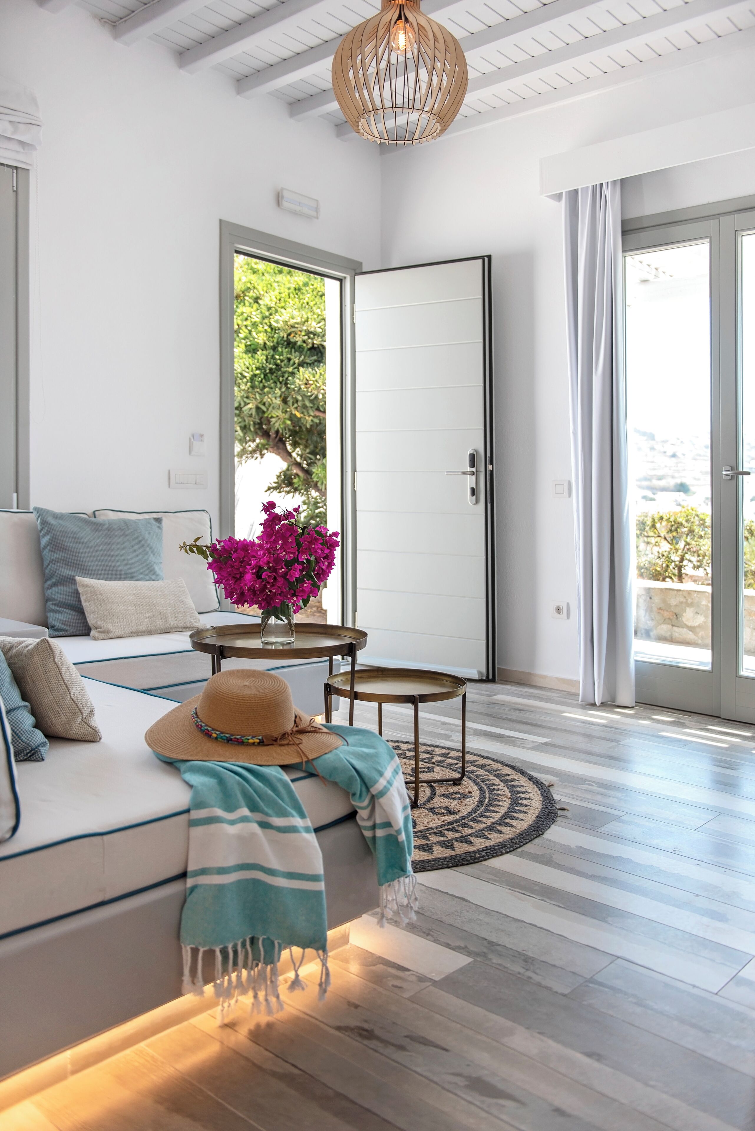 A modern living room with a sofa, a round table, a hat, and a vase of flowers.