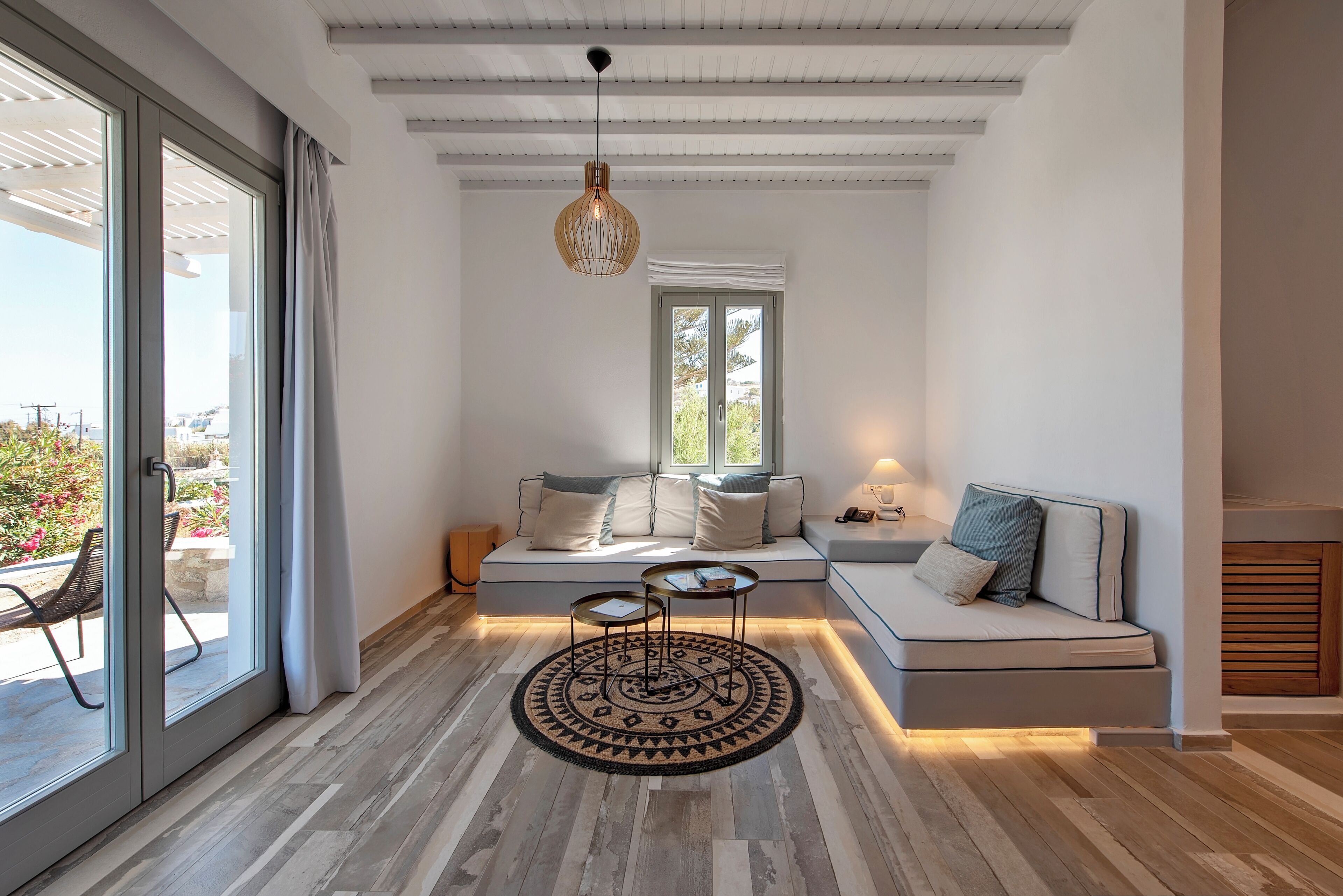 A modern living room with a sofa, a coffee table, and a hanging light fixture.