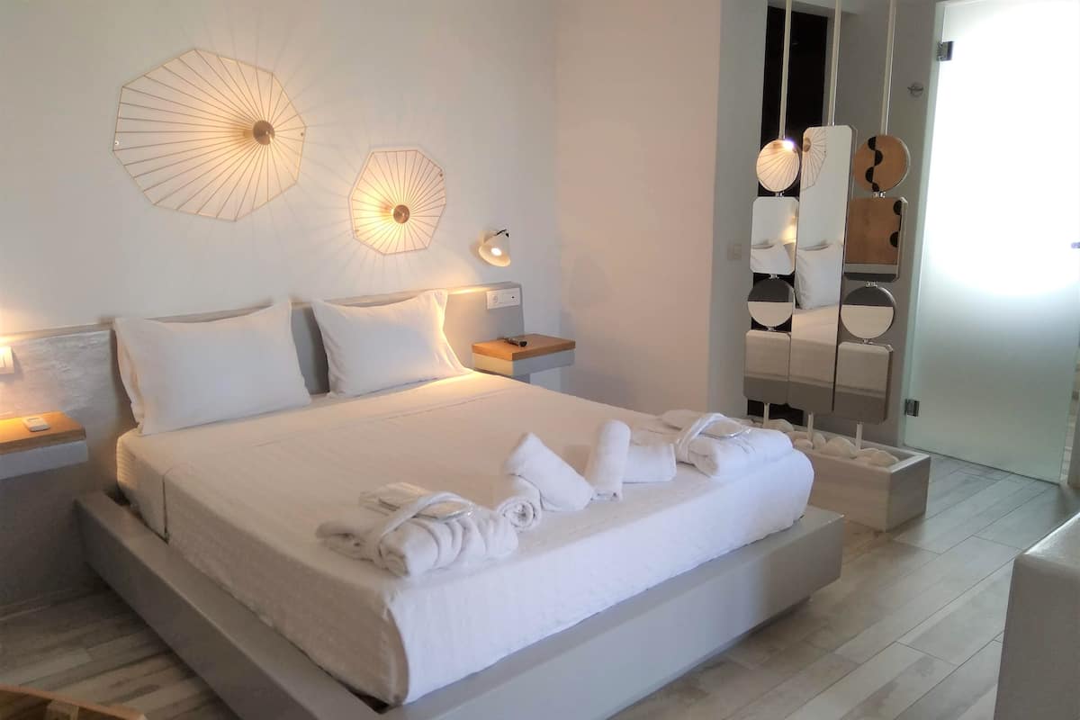 A modern hotel room with a large bed, two bedside lamps, and a mirror with a round mirror and two smaller mirrors.