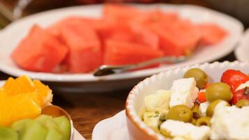 Una mesa con platos de sandía, un cuenco de aceitunas, queso feta y un bol de fruta.
