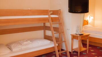 A bunk bed with a wooden ladder, a bedside table with a remote control, and a television mounted on the wall.