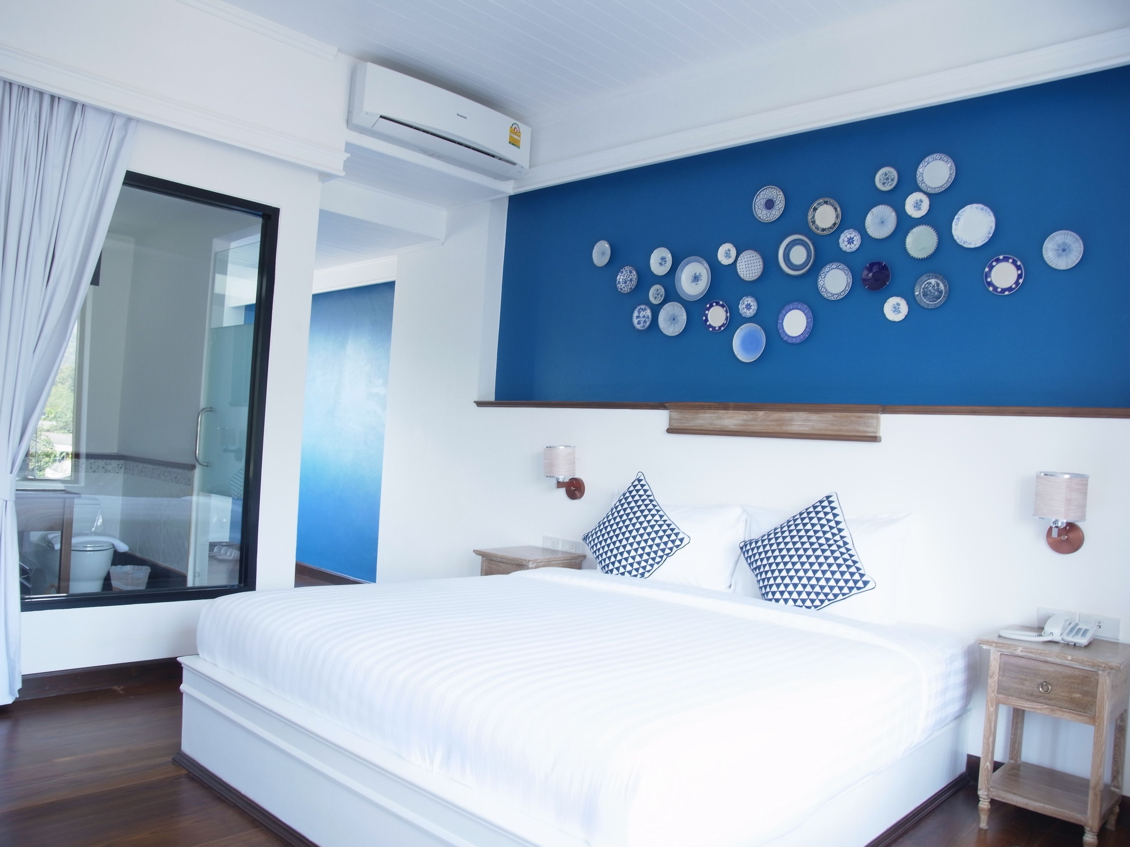 A bedroom with a large bed, a blue accent wall, and a collection of plates on the wall.