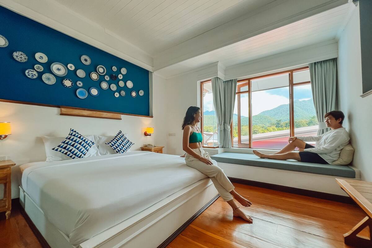 Ein Schlafzimmer mit einem großen Bett, einer Sitzgelegenheit am Fenster und einer Wand mit Tellern.