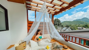 A balcony with a canopy, a view of mountains, and a table with food and drinks.