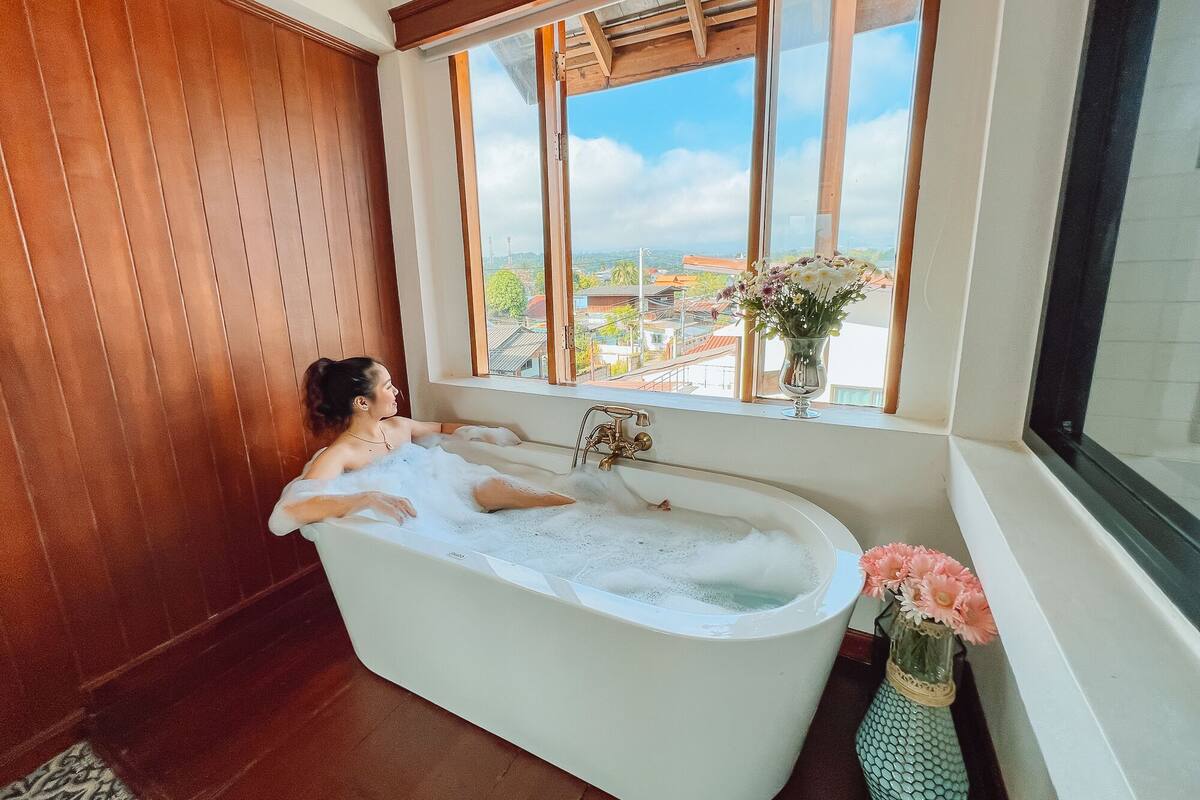 Eine Badewanne mit Blick auf eine Stadtlandschaft durch ein Fenster.