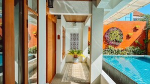 A narrow corridor with a pool on one side, leading to a wooden door.