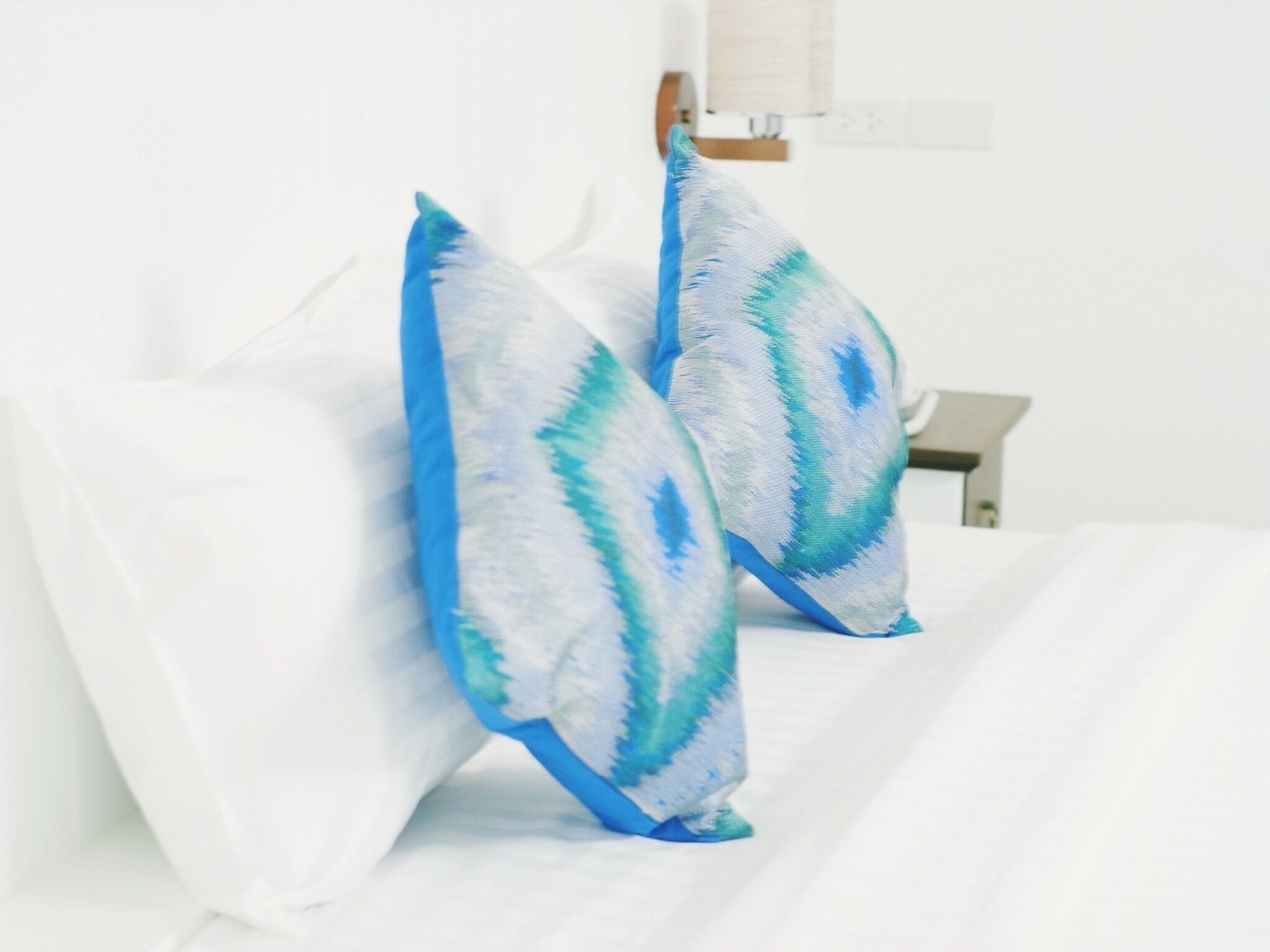 Two pillows with a blue and white pattern on a white bed.