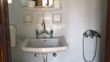 Un baño con lavamanos, espejo, ducha y un taburete pequeño.