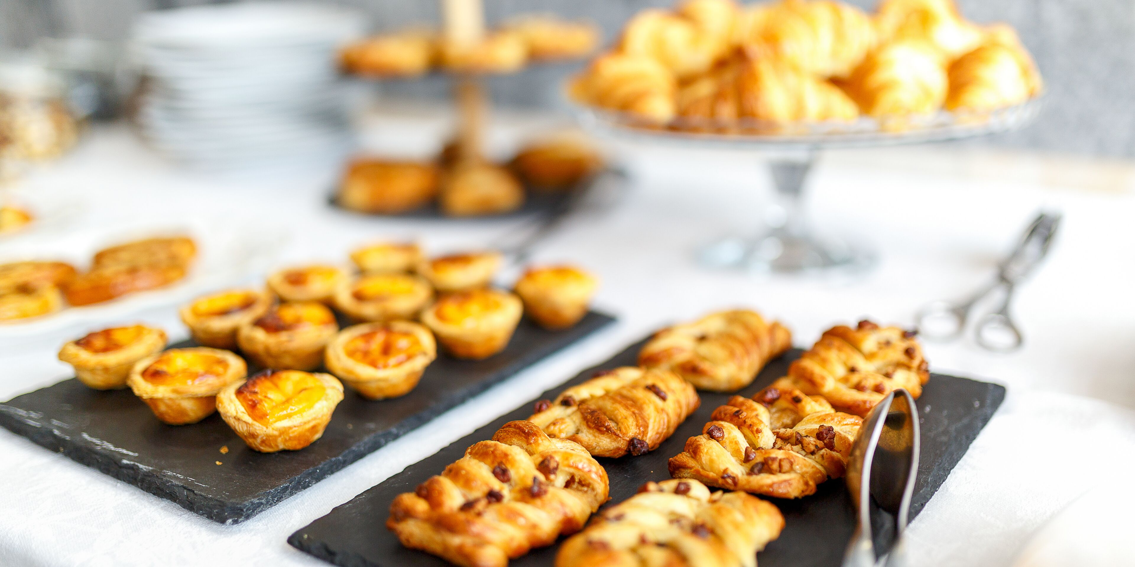 Une variété de viennoiseries présentées sur une planche de service en ardoise, notamment des tartes et des croissants.