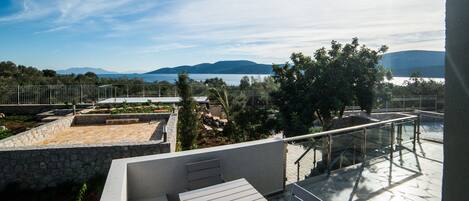 A terrace with a view of a lake and mountains, stone walls, and a hat on a table.