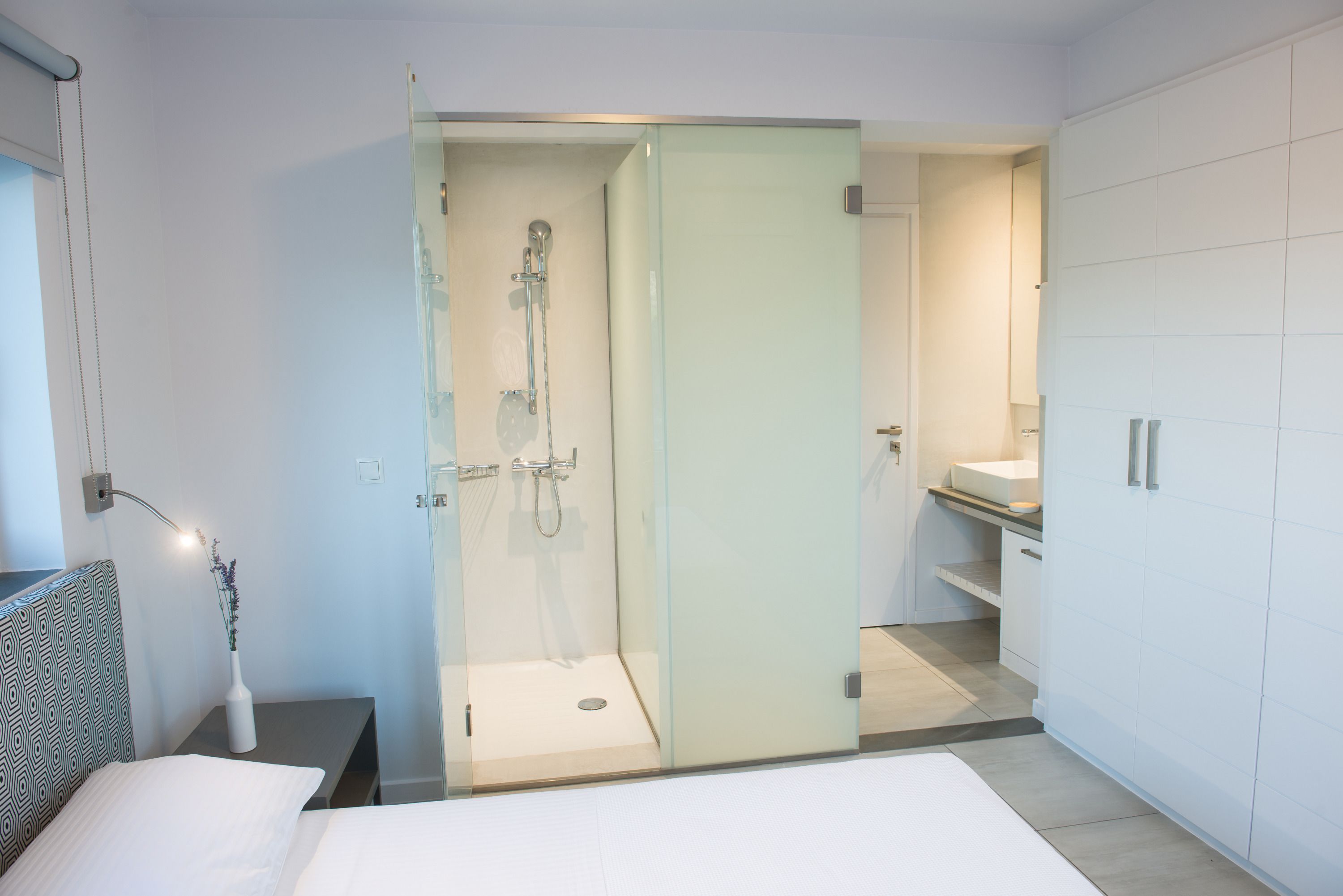Un baño moderno con cabina de ducha de vidrio, lavabo blanco y ducha a pie.