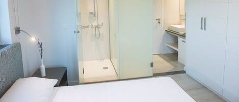 Un baño moderno con cabina de ducha de vidrio, lavabo blanco y ducha a pie.