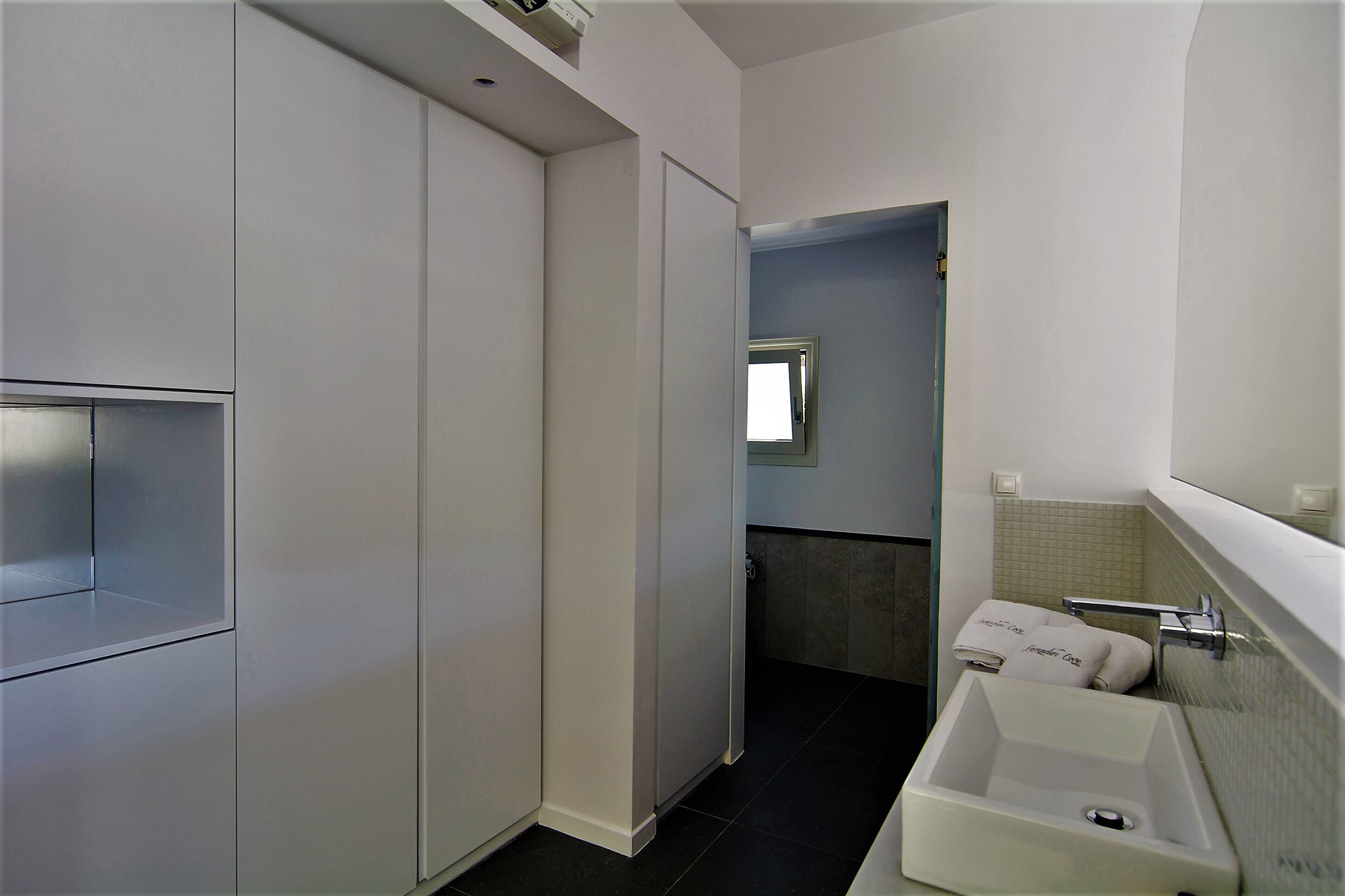 A modern bathroom with a large mirror, a sink, and a toilet.