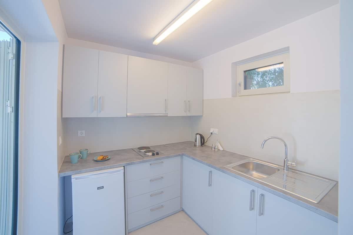 A compact kitchen with white cabinets, a built-in sink, and a window above the countertop.