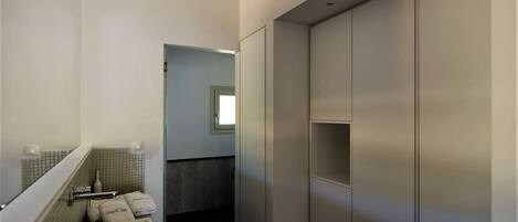 Un baño moderno con lavamanos, espejo, toallero y un vestidor.