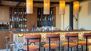 A bar area with a wooden bar counter, multiple liquor bottles, and bar stools.