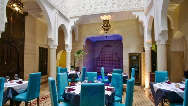A dining area with blue chairs and tables, white walls, and a patterned ceiling. - Riad Casa Lalla – Rooftop, Restaurant & Spa Medina (Marrakech)