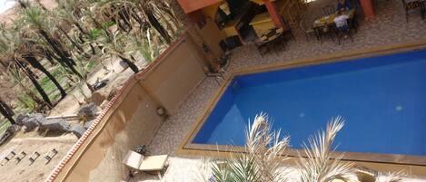 Een buitenzwembad, parasols bij het zwembad en ligstoelen