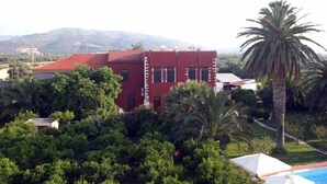 Un edificio rojo rodeado de exuberante vegetación y palmeras.