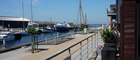 A marina with boats docked, a wooden walkway, and a building with a balcony.