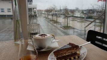 A table with a slice of cake, a cup of coffee, and a glass of whiskey.