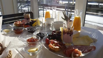 Uma mesa de café da manhã com diversos alimentos, incluindo frutas, queijos e carnes.