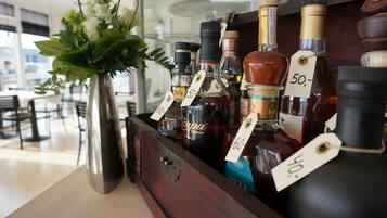 A wooden bar display with various bottles of liquor, each with a price tag.