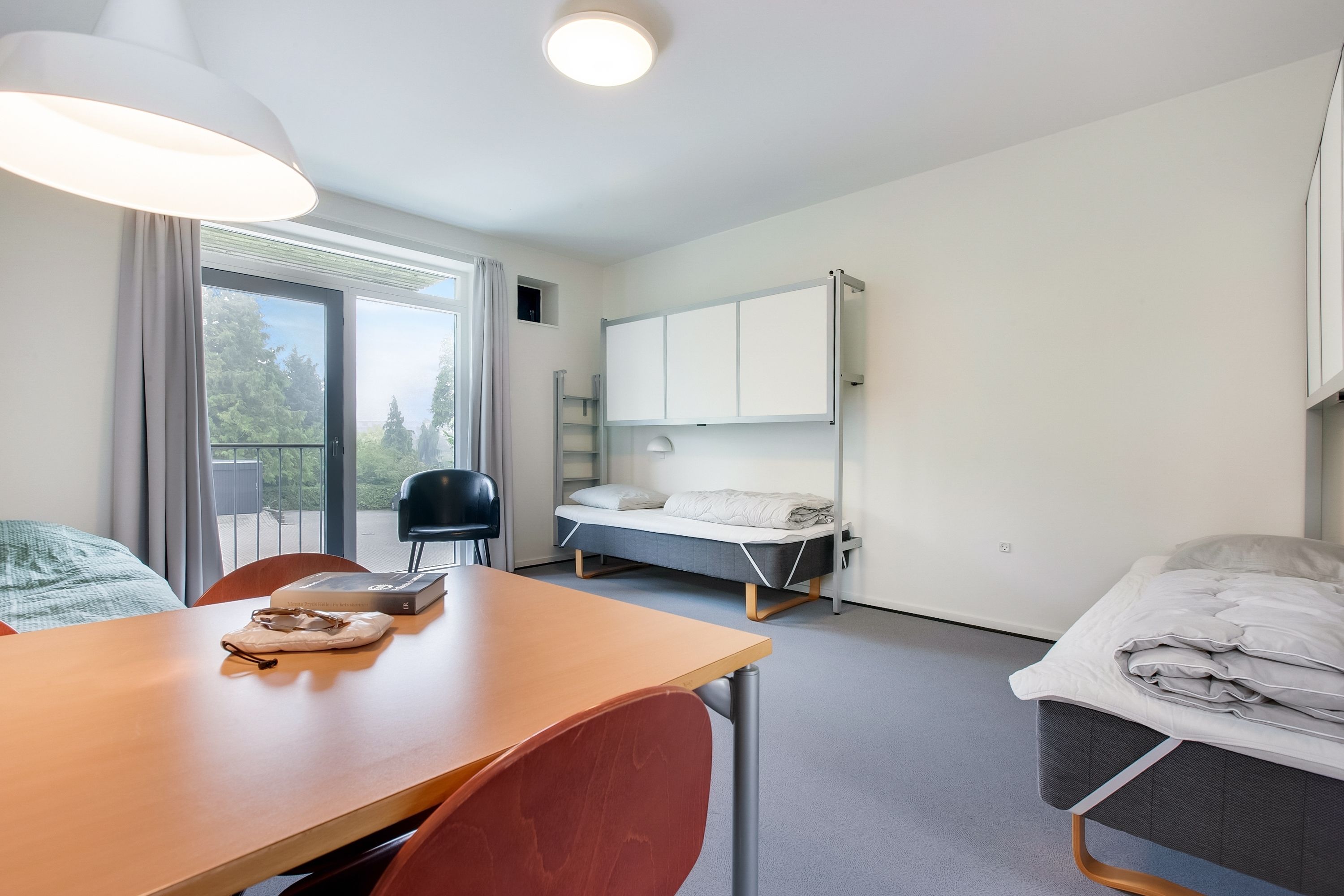 A modern, well-lit room with a bed, a desk, and a chair.