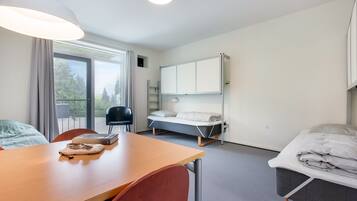 A modern, well-lit room with a bed, a desk, and a chair.