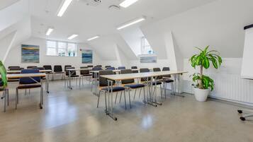 A classroom with desks and chairs arranged in rows, a projector, and a large window with a view.