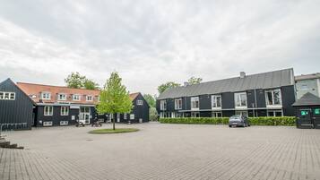 A courtyard with buildings, a car, and a tree.