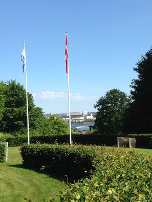 Two flagpoles with flags, a grassy area, and a distant view of buildings and a body of water. - Danhostel Kolding (Kolding)