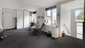 A modern office space with a black and white color scheme, featuring a meeting table, chairs, a radiator, and a window with a view of the outside. - Danhostel Kolding (Kolding)