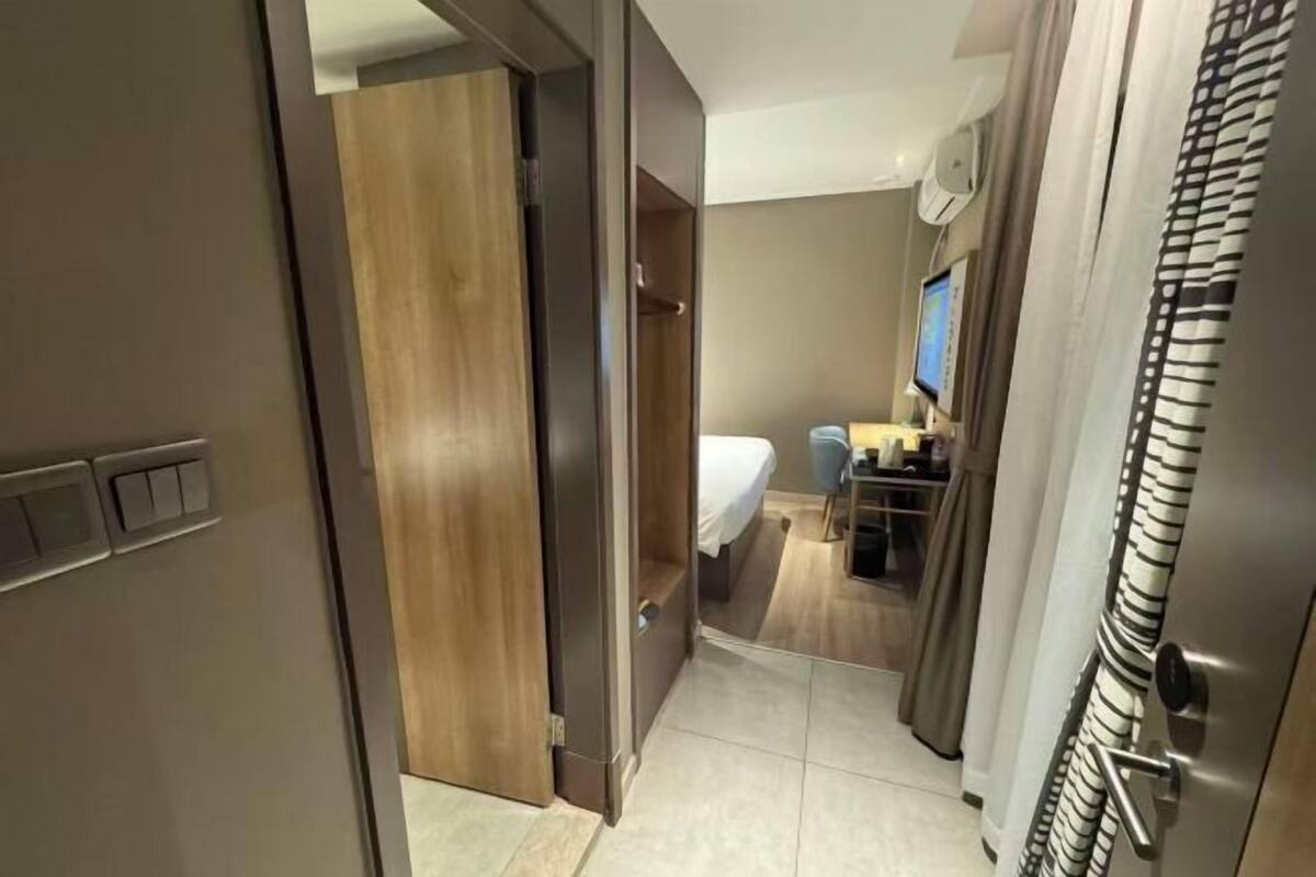 A hotel room with a bed, a desk with a computer, a TV, and a bathroom with a shower curtain.