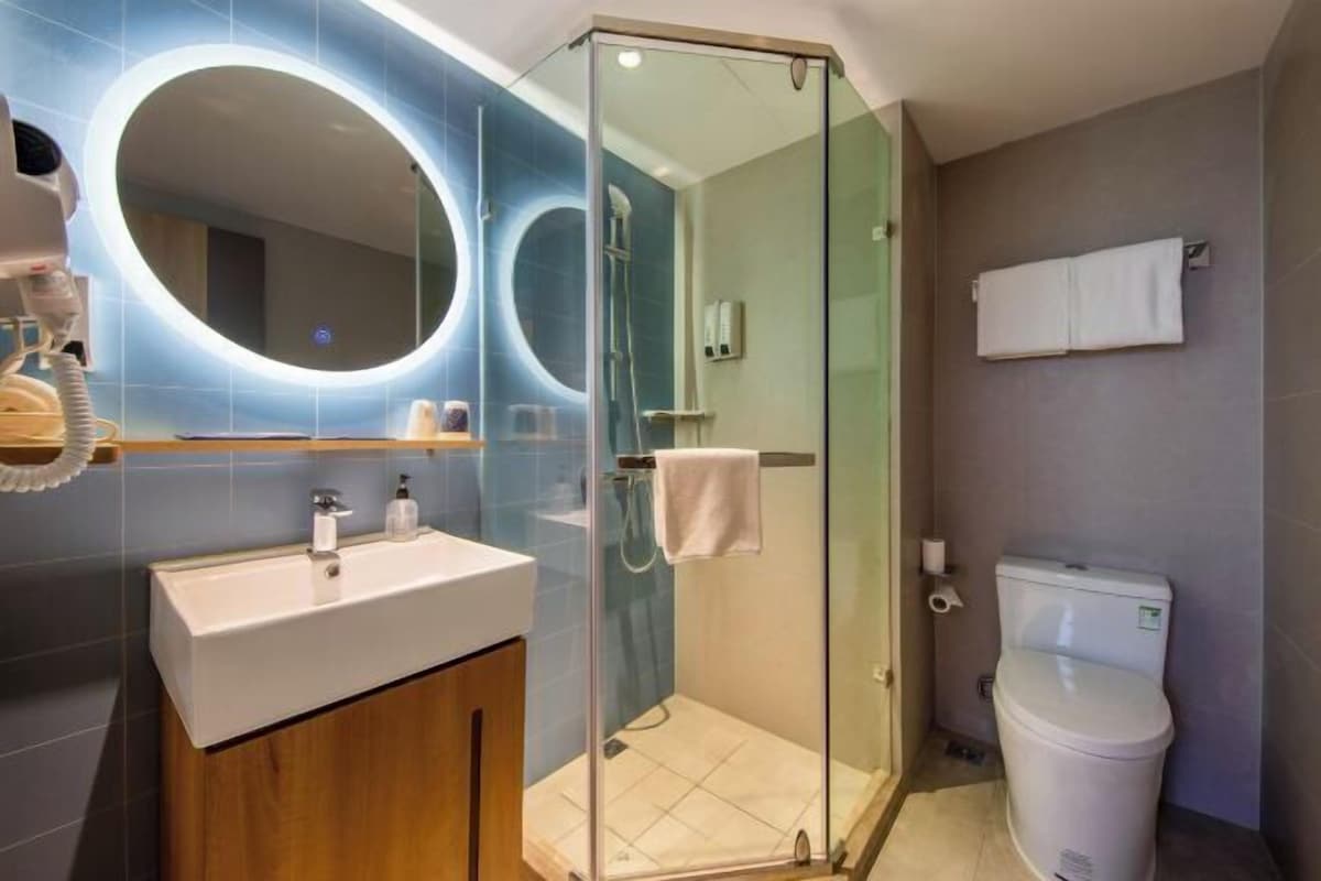 A modern bathroom with a glass-enclosed shower, a sink with a mirror, and a toilet.