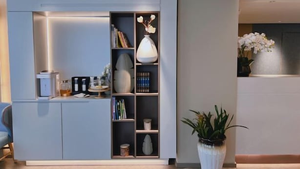 Un salon moderne avec une bibliothèque intégrée, une machine à café et une plante en pot.