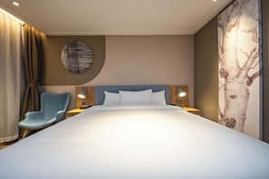 A modern hotel room with a large bed, a blue chair, a round wall decoration, and a tree mural on the wall. - Homeinn · neo Hotel (Kunming Beijing Road Dongfeng Square Subway Station) (Kunming)