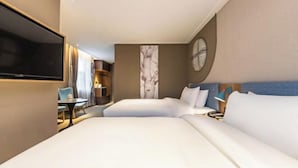 Une chambre d’hôtel avec un grand lit, un téléviseur à écran plat, une petite table et une chaise.