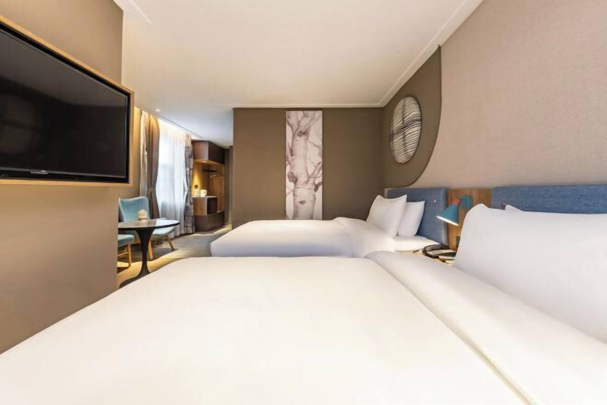 A hotel room with a large bed, a flat-screen TV, a small table, and a chair.