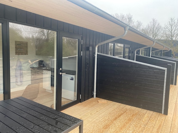 A modern building with a wooden deck, a glass door entrance, and a metal gate. - Sportsby Vejen (Vejen)