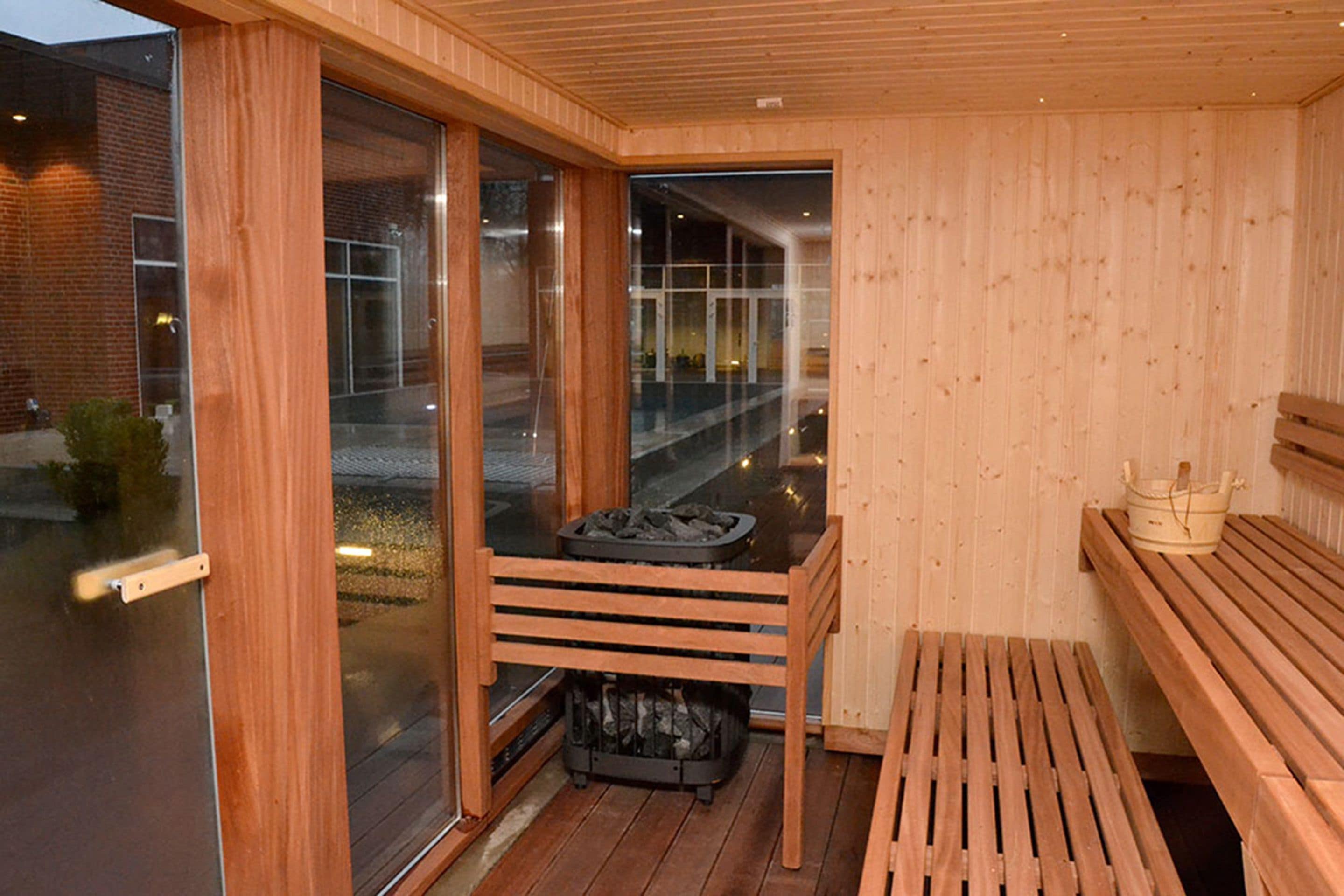 Una sauna con bancos de madera, una puerta de vidrio y vistas al exterior.